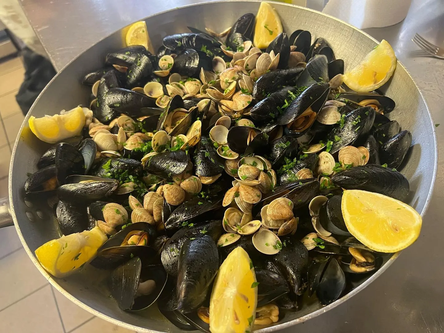 Padella di cozze e vongole con limone servita in tavola
